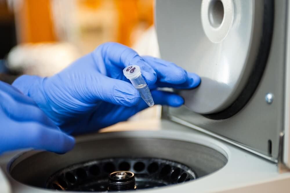 Gloved hands loading a centrifuge with samples Gloved hands loading a centrifuge with samples