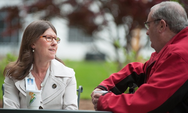 Mass General patient advocate sitting on a bench working with a patient. Mass General patient advocate sitting on a bench working with a patient.