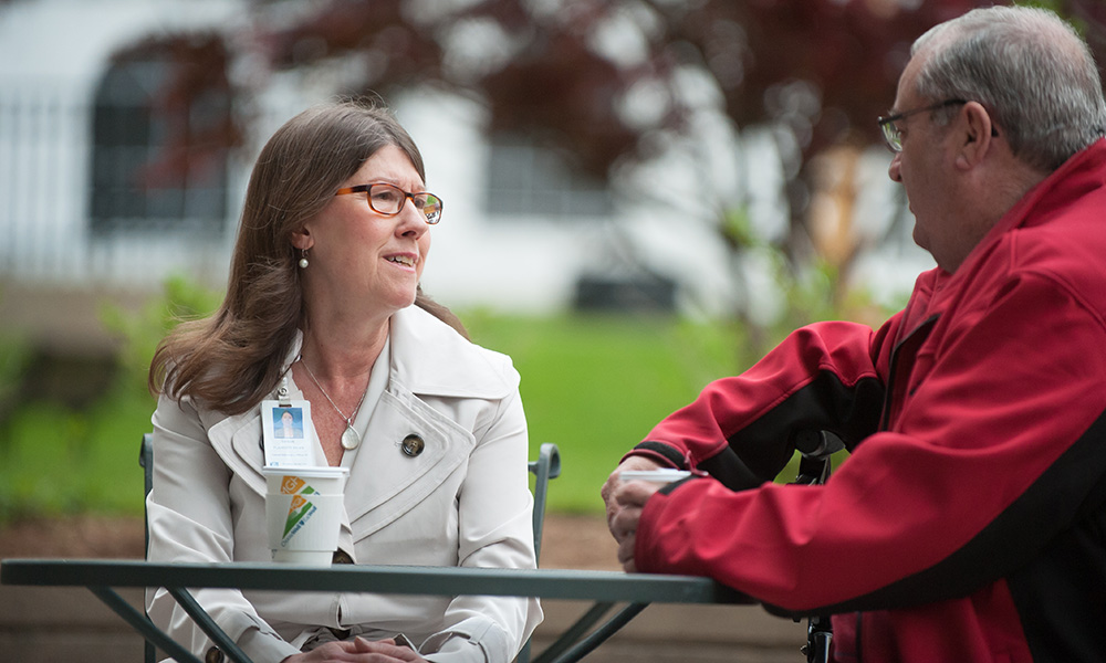 Mass General patient advocate sitting on a bench working with a patient. Mass General patient advocate sitting on a bench working with a patient.