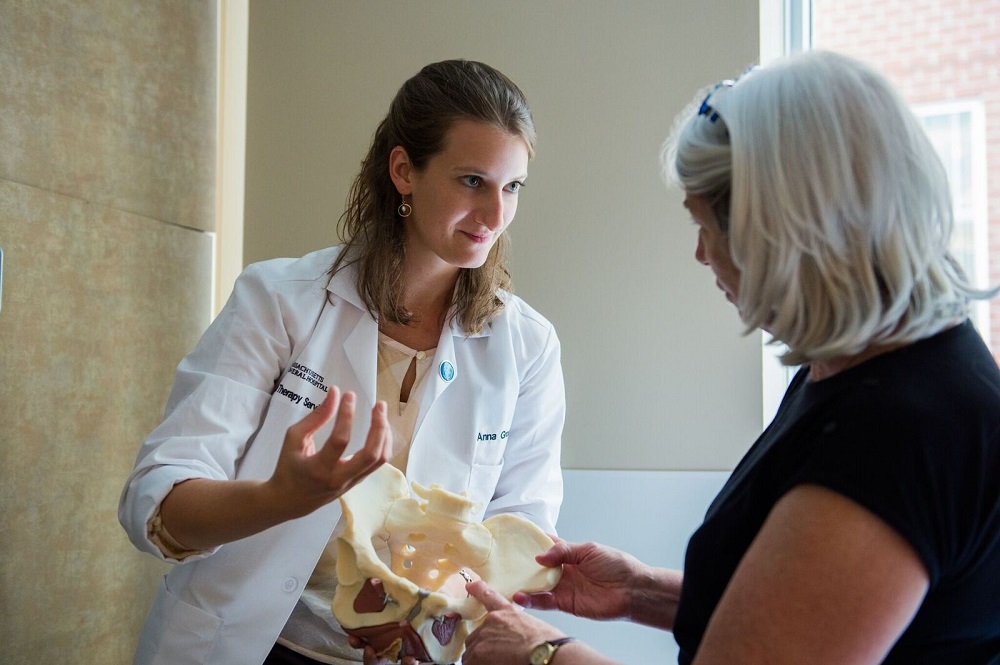 Physical therapist Anna Benedix and a patient examine a model of the female pelvis.
