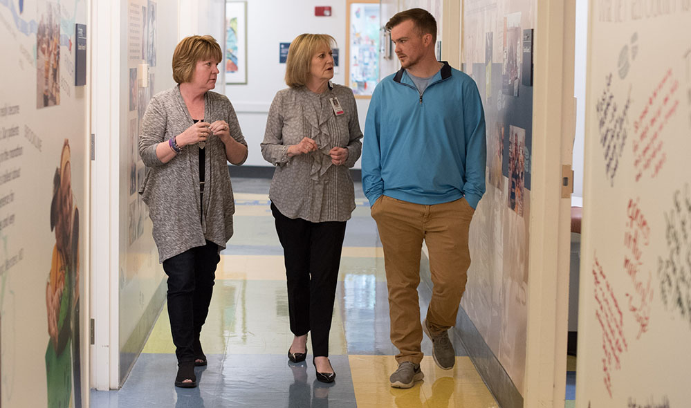 Social worker speaking with mother and son in hallway. Social worker speaking with mother and son in hallway.
