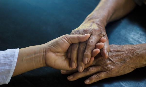 A closeup of a child's hand holding an elderly person's hand A closeup of a child's hand holding an elderly person's hand