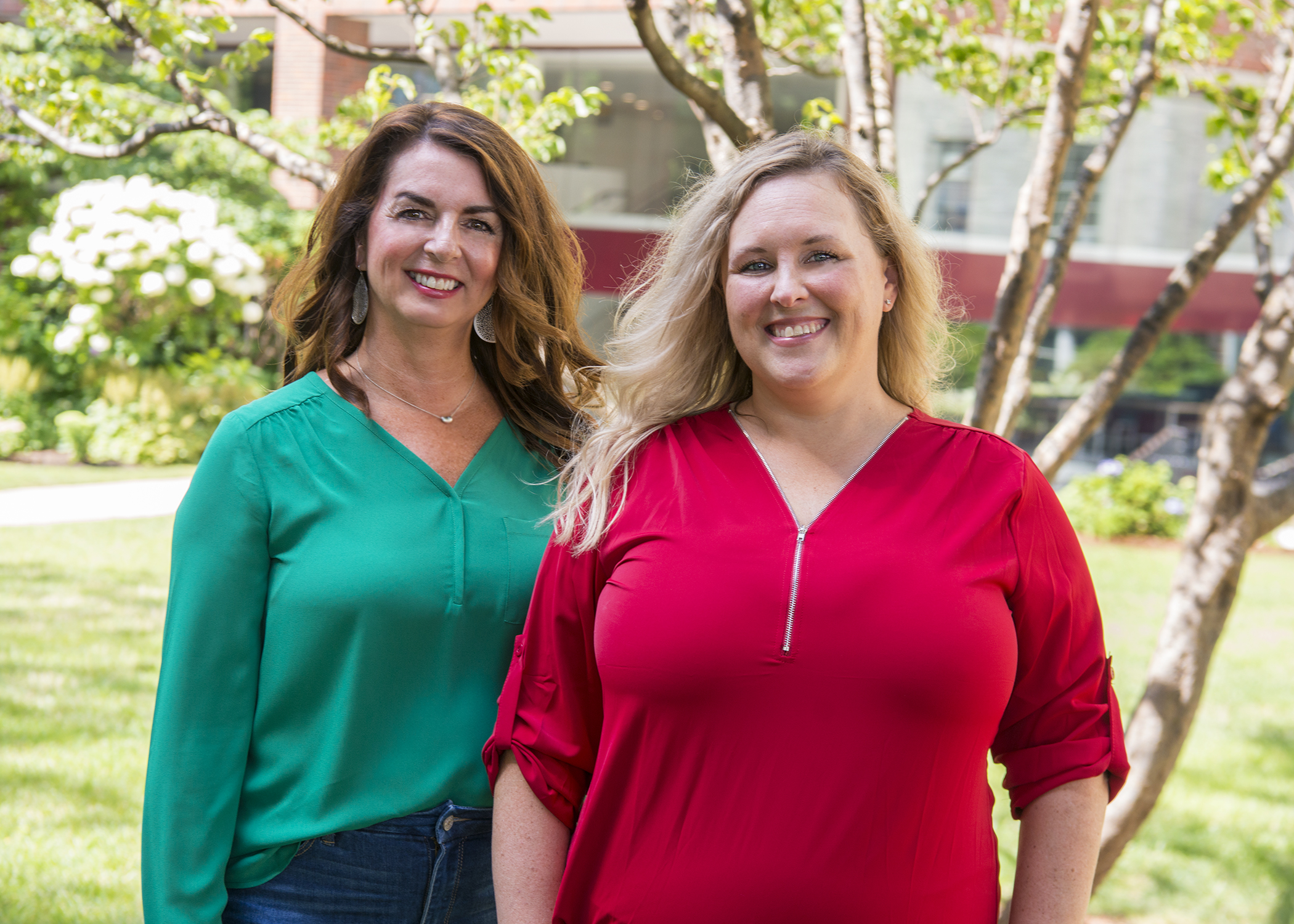 Two women standing side-by-side and smiling. Two women standing side-by-side and smiling.