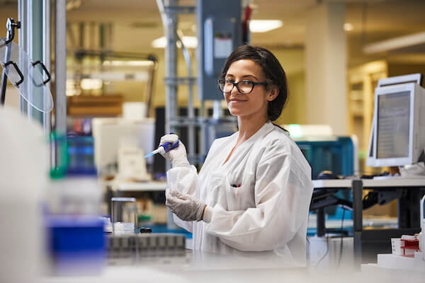 Researcher with pipette tool smiles at camera Researcher with pipette tool smiles at camera