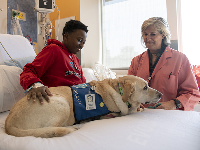 Teenaged patient and volunteer with a pet therapy dog Teenaged patient and volunteer with a pet therapy dog